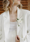 Close up of the white Haven boutonniere pinned to a white suit lapel