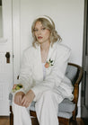 A woman in a white suit wearing a Chelle collection corsage