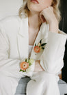A woman in a white suit wearing a Chelle collection corsage