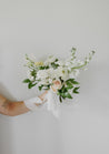 A woman with a tattoo on her inner arm holds a small Haven bridesmaid bouquet