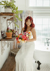 A bride with flowing red hair gazes down at the Wylder bridal bouquet in her hands