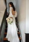 Bride standing on a staircase with open-backed wedding dress, holding a Haven Bridal Bouquet